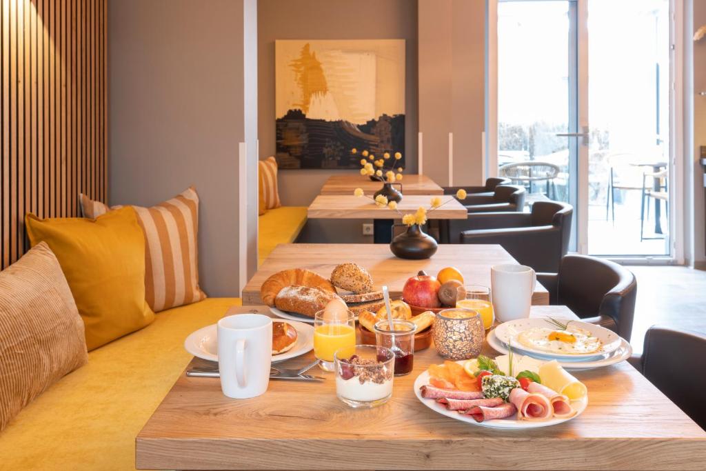 a table with breakfast foods on it in a living room at Hotel Tide42 in Borkum