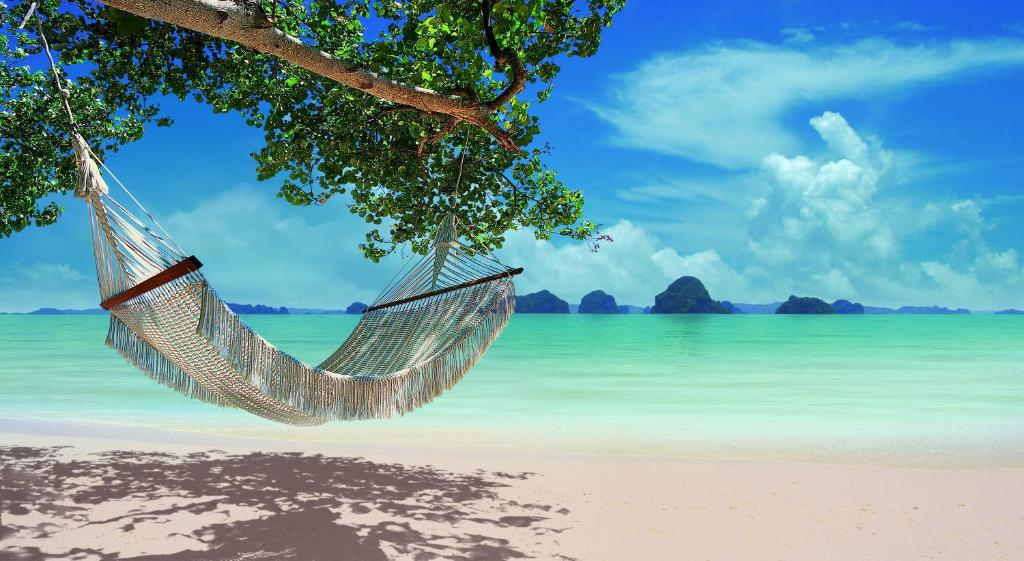 a hammock hanging from a tree on a beach at The Tubkaak Krabi Boutique Resort - SHA Extra Plus in Tab Kaek Beach