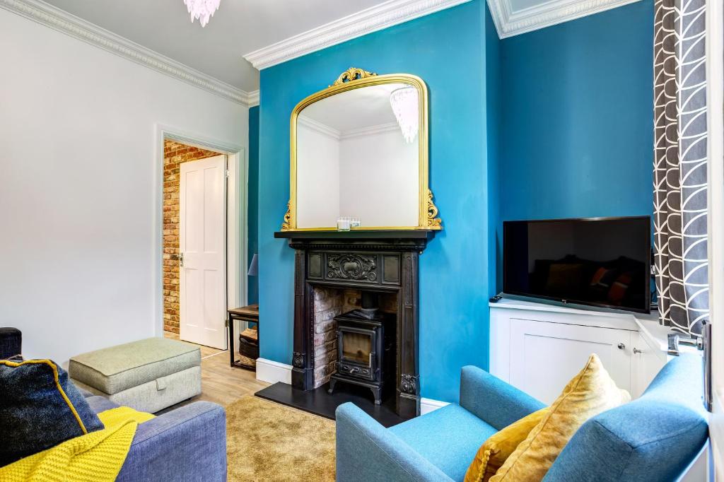 uma sala de estar azul com lareira e espelho em Woodside Cottage, Congleton, Nr Peak District em Congleton