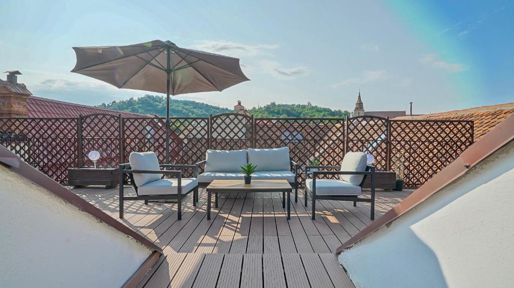 een patio met een tafel en stoelen en een parasol bij Comfort Apartment Rooftop Brasov in Braşov