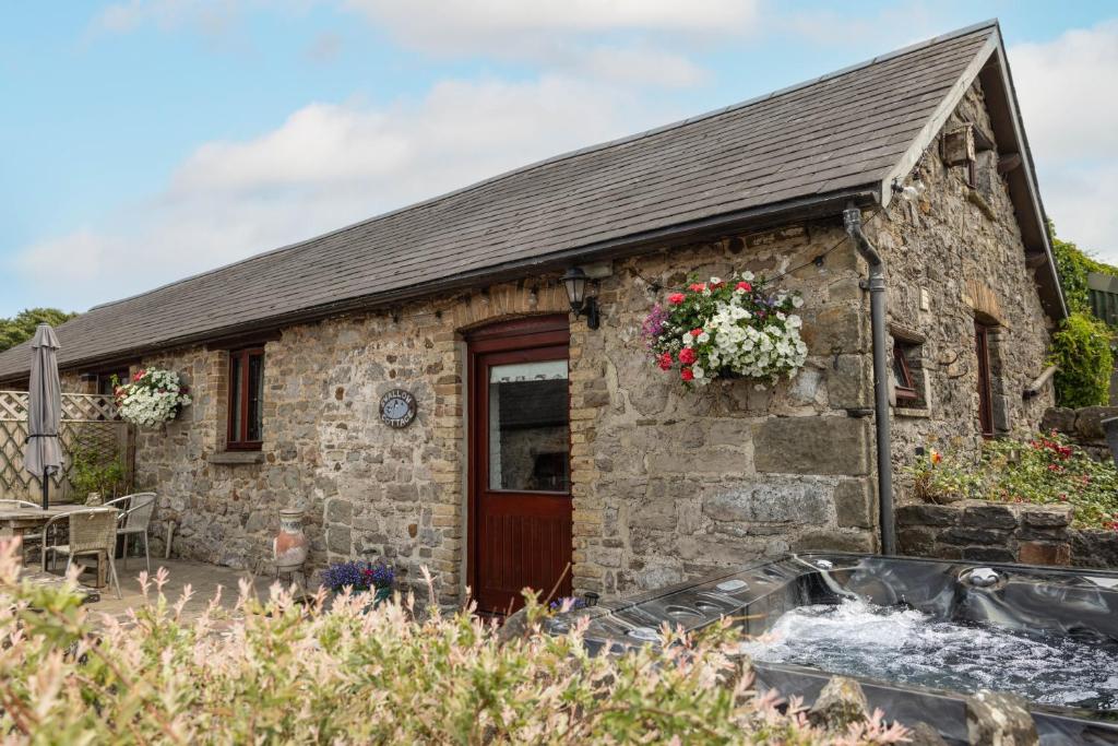 a stone cottage with a red door at Swallow Cottage in Bridgend