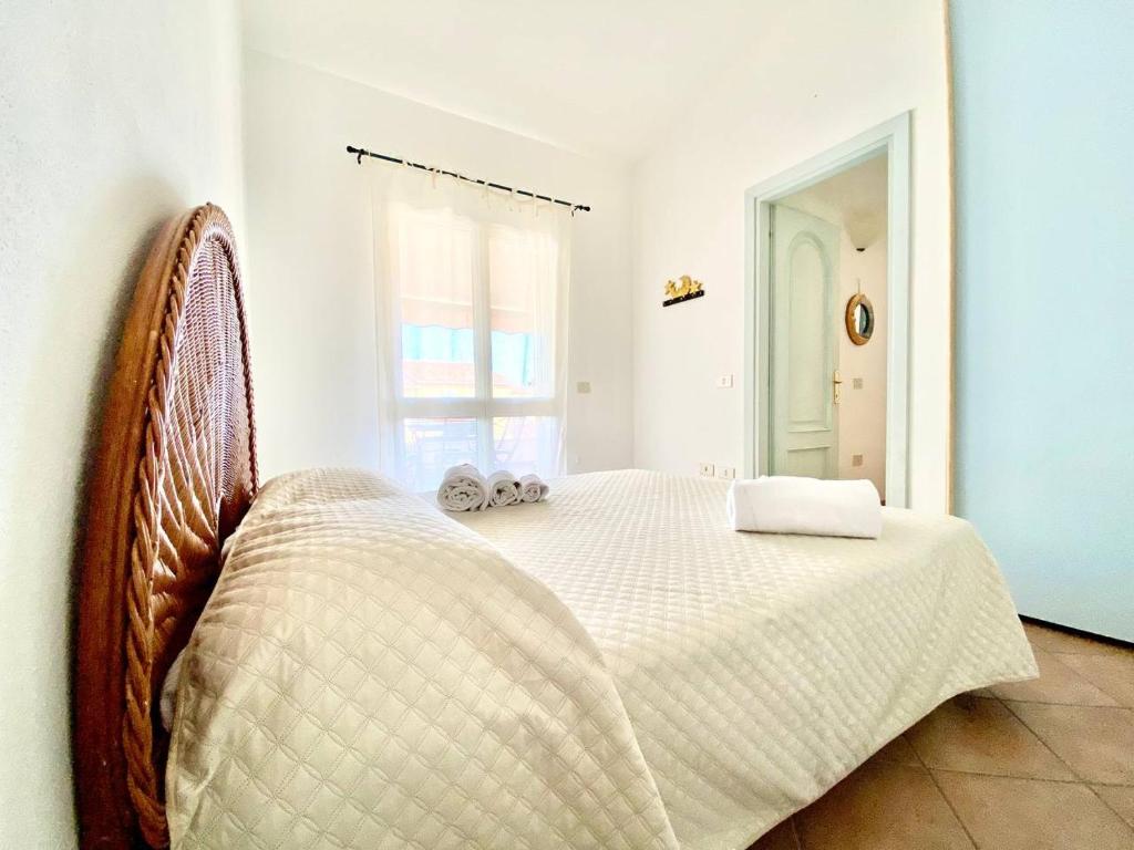 1 dormitorio con 1 cama blanca y 2 toallas en Casagliana Apartments en Golfo Aranci