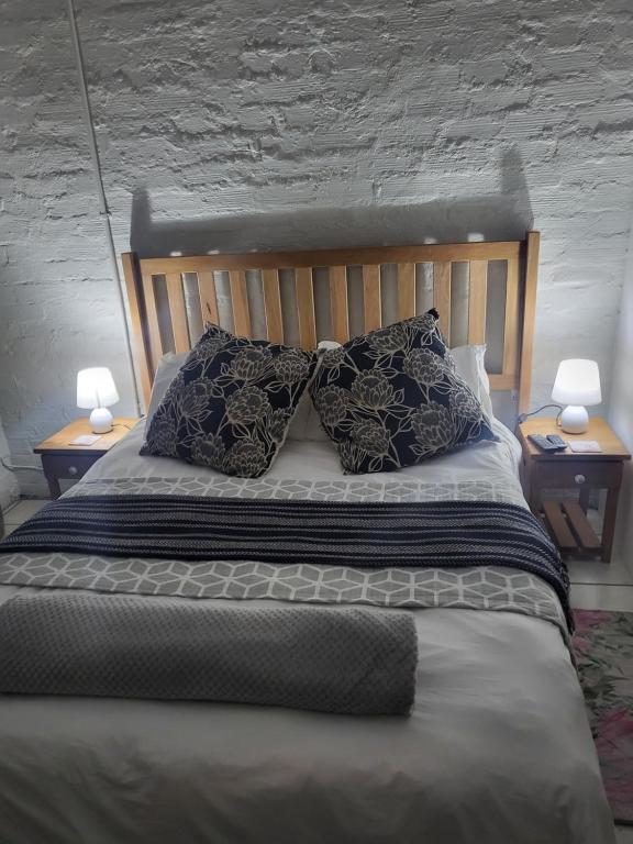 a bedroom with a bed with pillows and two lamps at 9 on Oostersee in Cape Town