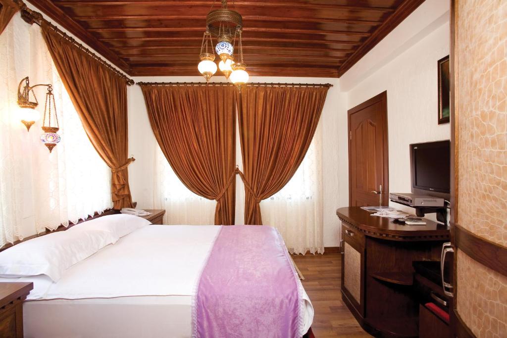 een slaapkamer met een bed, een bureau en een televisie bij Cicerone Lodge Hotel in Antalya