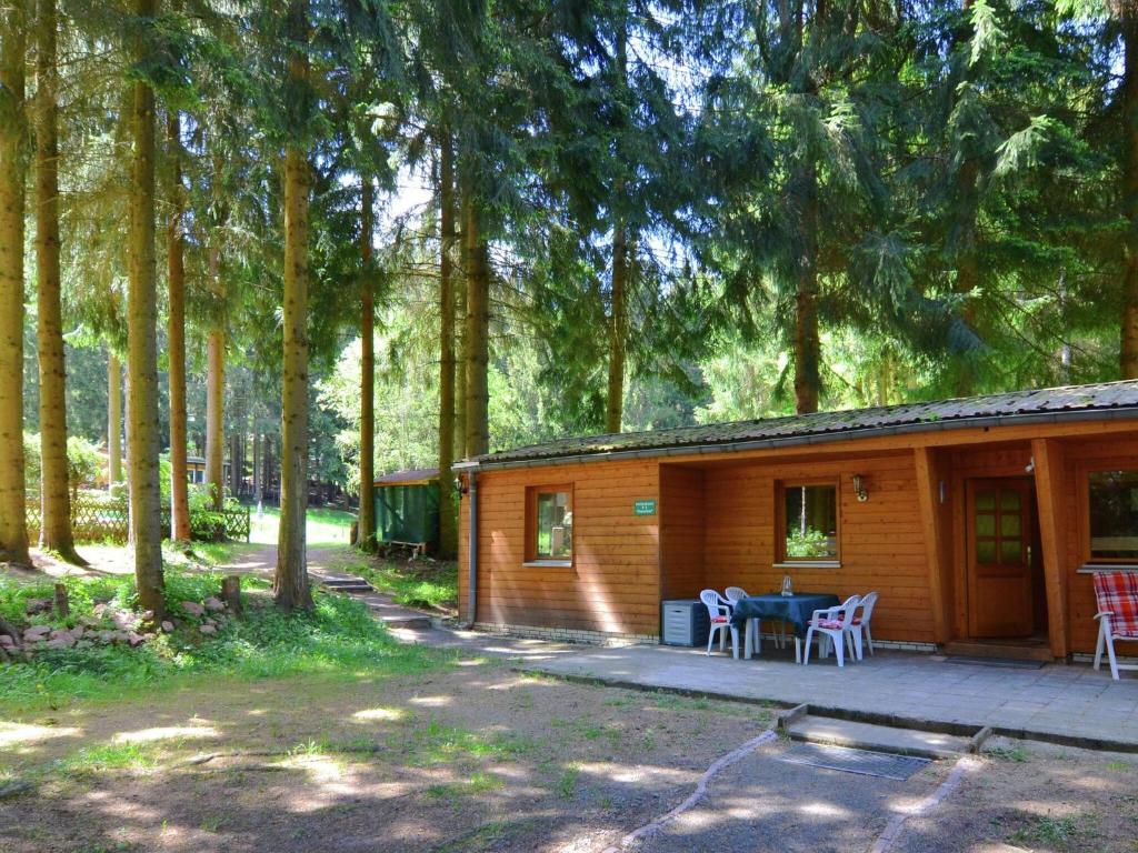 uma cabana na floresta com uma mesa e cadeiras em Cosy apartment with covered porch em Finsterbergen