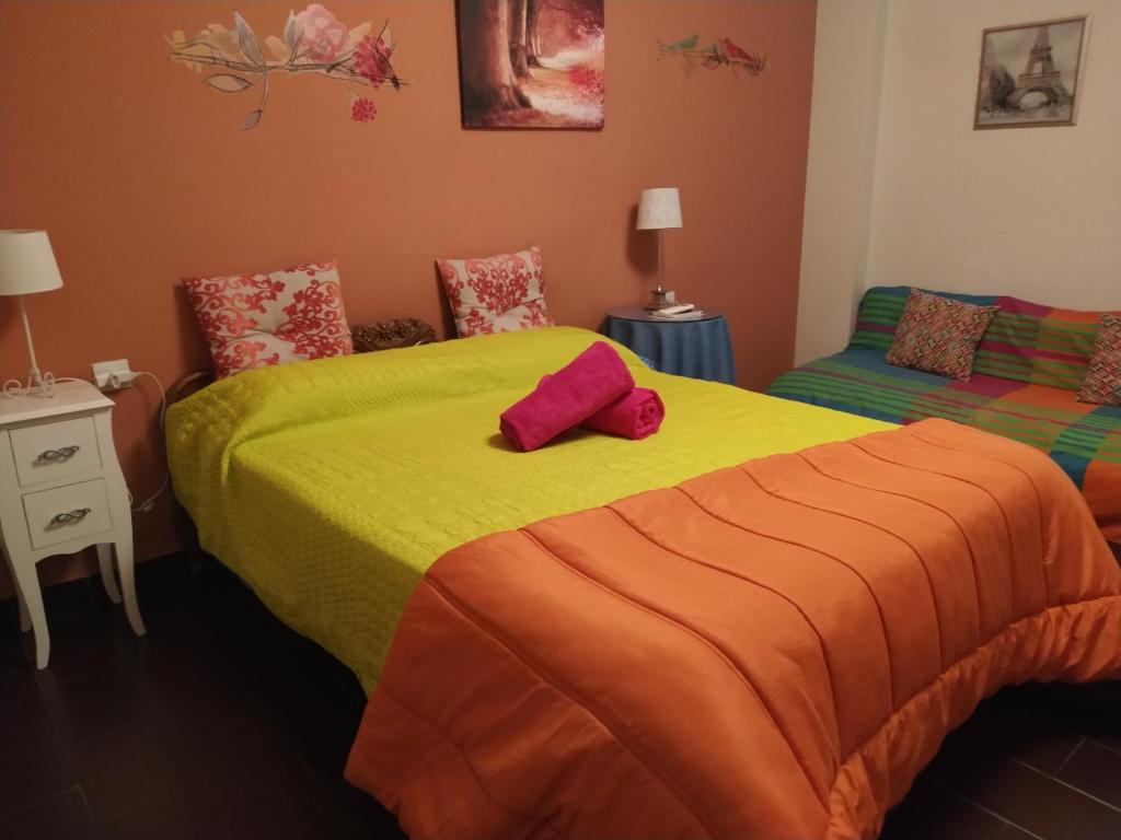 a bedroom with two beds with yellow and orange sheets at Apartamento San Anton in Granada