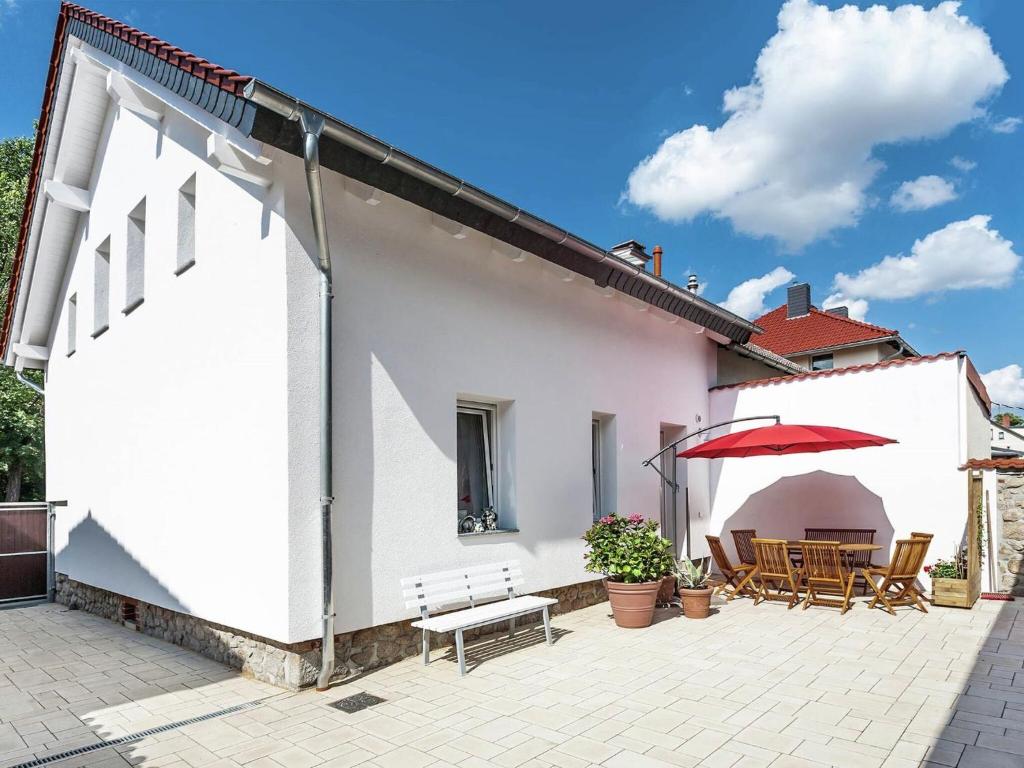 ein weißes Haus mit einer Terrasse mit einem Tisch und einem Sonnenschirm in der Unterkunft Bright apartment in Thale with terrace in Thale
