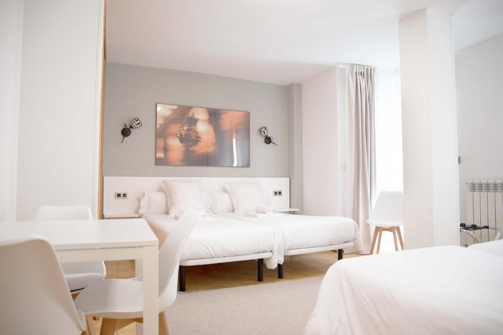 Habitación blanca con 2 camas y espejo. en Stellae Luscofusco en Santiago de Compostela