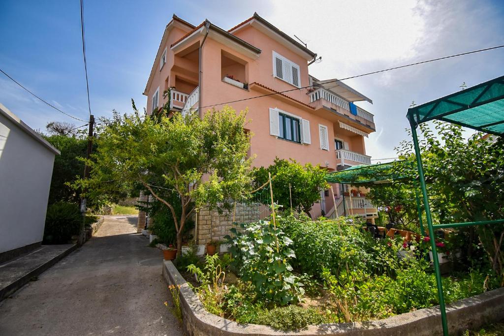 een roze huis met een tuin ervoor bij Rooms Anđela in Rab