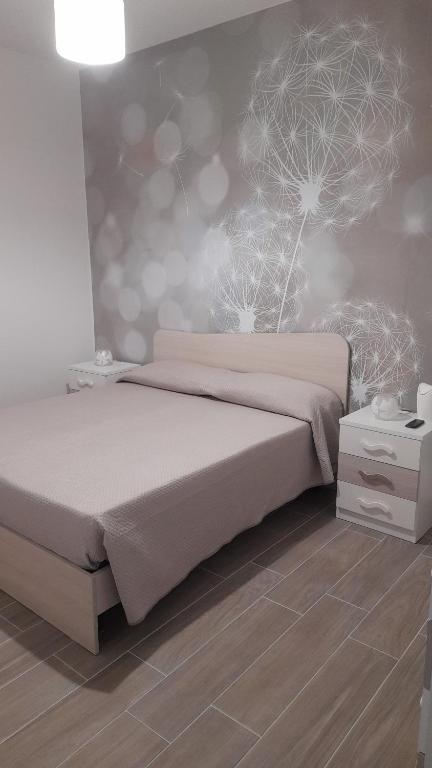 ein Schlafzimmer mit einem Bett und einer Wand mit Löwenzahn in der Unterkunft B&B Green House in Villapiana