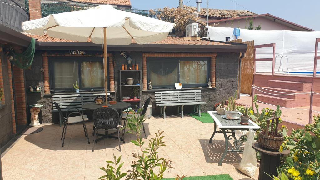 patio con tavolo, sedie e ombrellone di House dependance Belvedere a Misterbianco