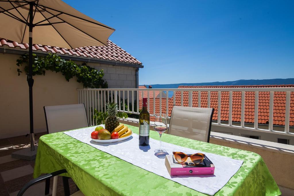 a table with a plate of fruit and a bottle of wine at Aurora Apartments in Bol