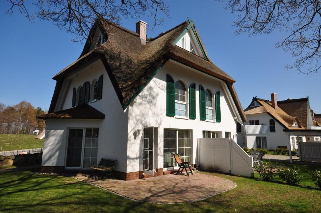 a large white house with green windows and a roof at Ferienhaus Am Strand in Zingst