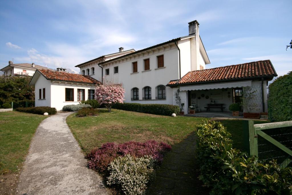 une grande maison blanche avec un chemin en face de celle-ci dans l'établissement Villa Piera, à Belluno