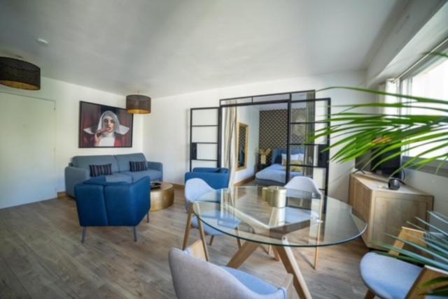 a living room with a glass table and blue chairs at MYAPPARTBORDEAUX in Bordeaux