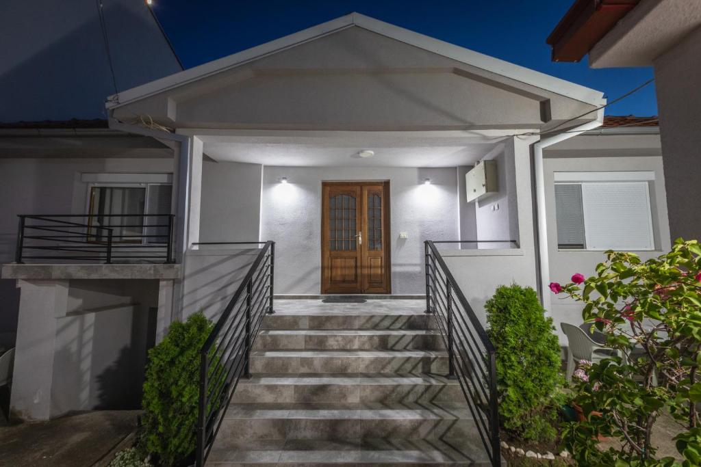 a white house with stairs and a wooden door at Guest House - Axios in Gevgelija