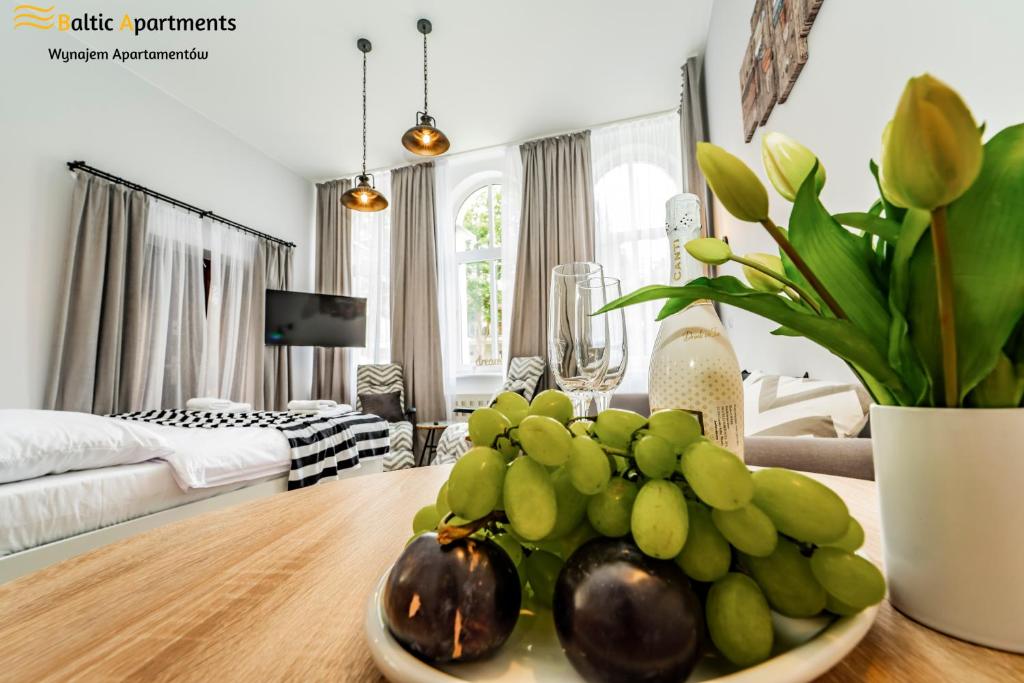 ein Wohnzimmer mit einer Obstschale auf dem Tisch in der Unterkunft Baltic Apartments - Willa Carmen in Świnoujście