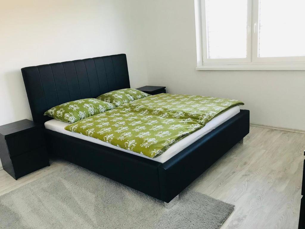uma cama com uma moldura preta e lençóis e almofadas verdes em Villa Rosé Lehnice em Lehnice