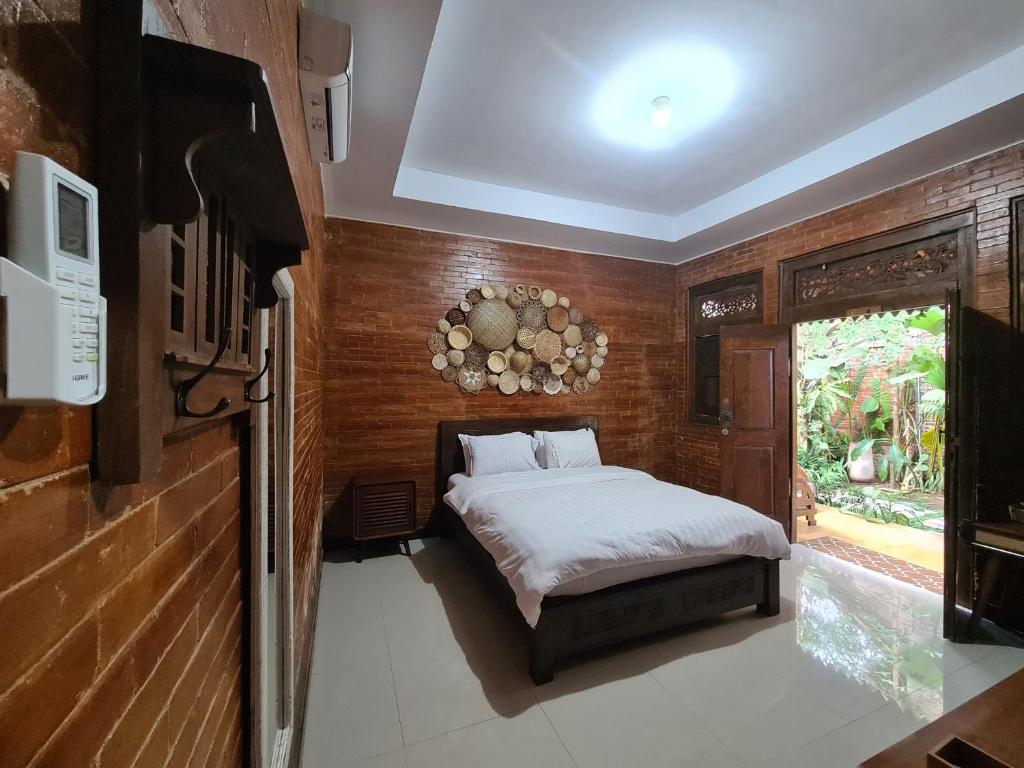 1 dormitorio con 1 cama en una pared de madera en La Tavisa Hotel Borobudur en Magelang