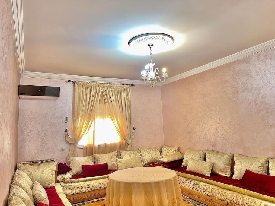 een woonkamer met een grote bank en een tafel bij Appartement en résidence (shahid,clim,wifi…) in Marrakesh