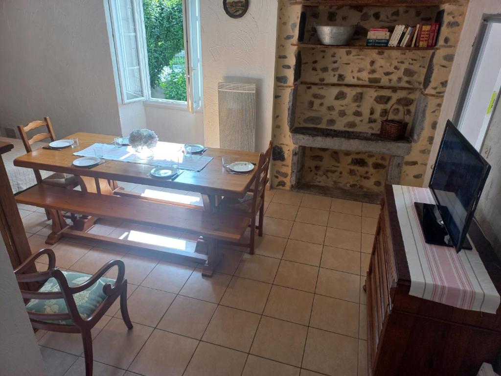 a dining room with a wooden table and a fireplace at Maison avec jardin in Adé