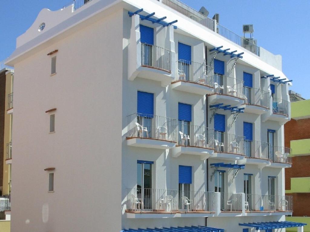 biały budynek z niebieskimi oknami i balkonami w obiekcie Vibrant Apartment in Rimini with Balcony w Rimini