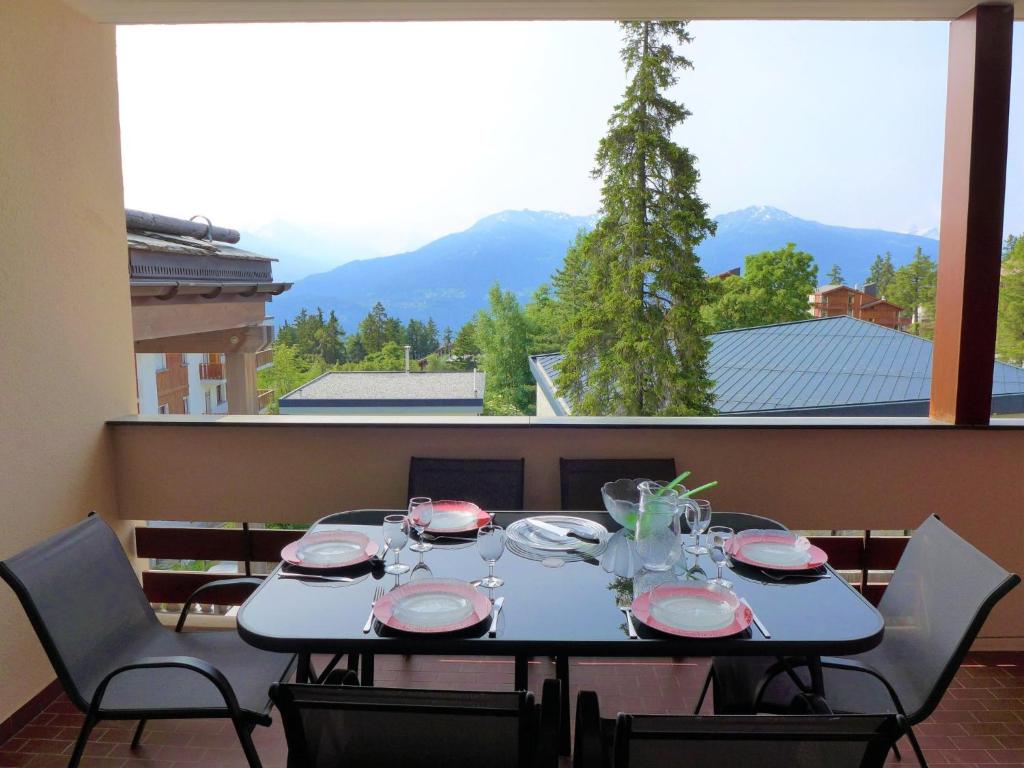einen Tisch mit Tellern und Gläsern mit einem großen Fenster in der Unterkunft Apartment Genziana by Interhome in Crans-Montana