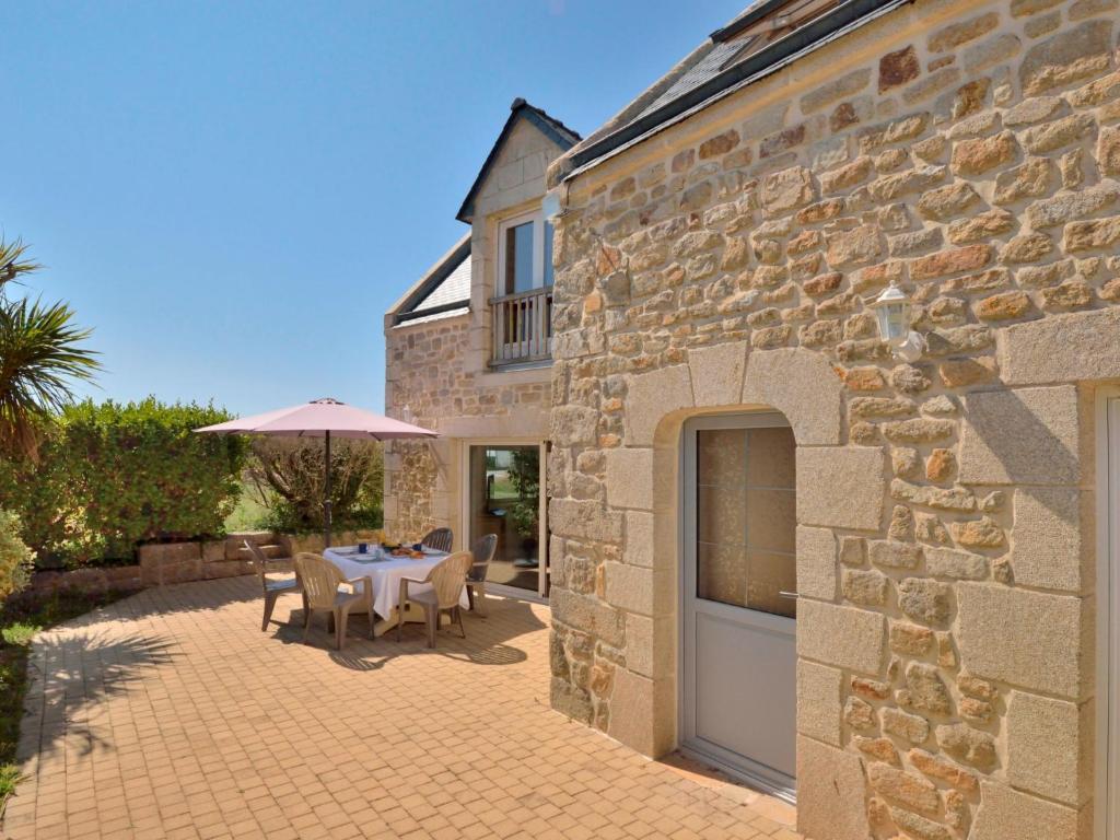 une maison en pierre avec une table et un parasol dans l'établissement Holiday Home Tazie by Interhome, à Plouhinec