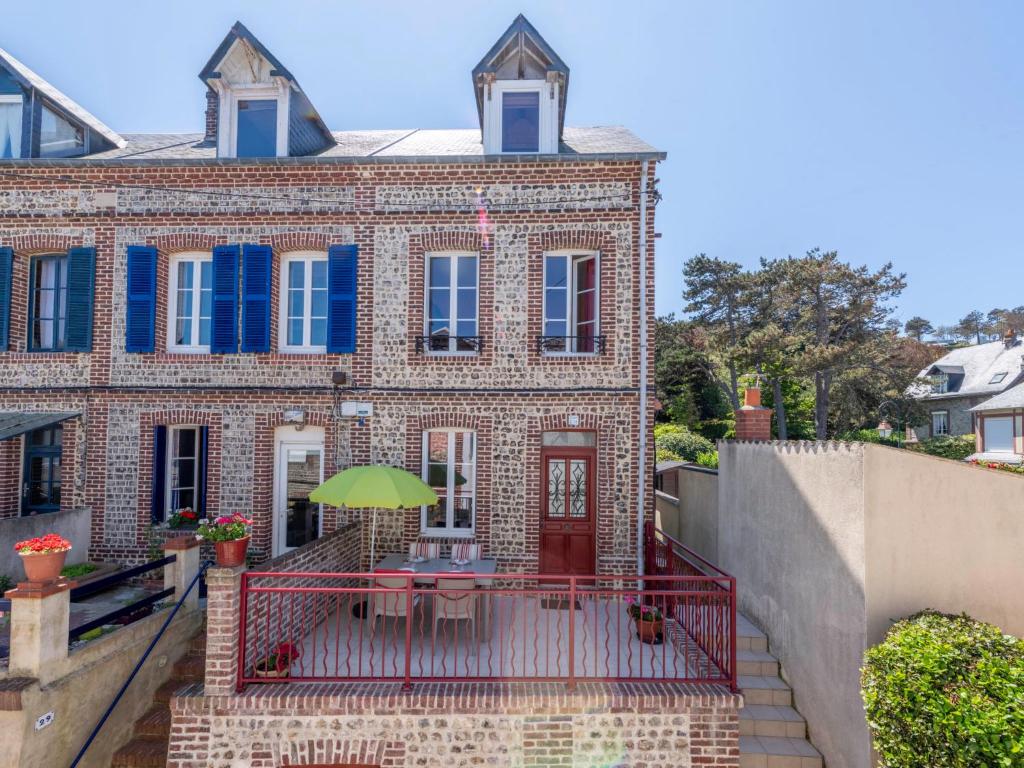 a brick house with a balcony with a green umbrella at Holiday Home La Rose des Vents - YPO401 by Interhome in Yport