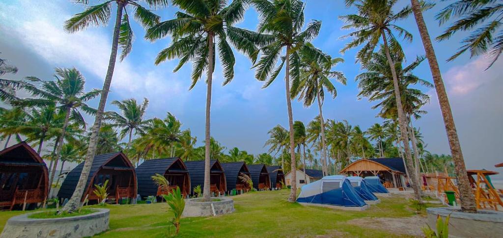 PadangnegeriにあるPalma Beach Resortのヤシの木やテントが並ぶ家並み