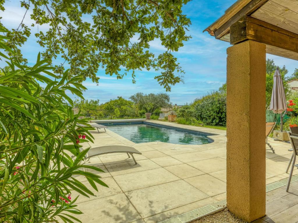 eine Terrasse mit einem Pool, einem Tisch und Stühlen in der Unterkunft Holiday Home Le Chêne - SRX100 by Interhome in Sabran