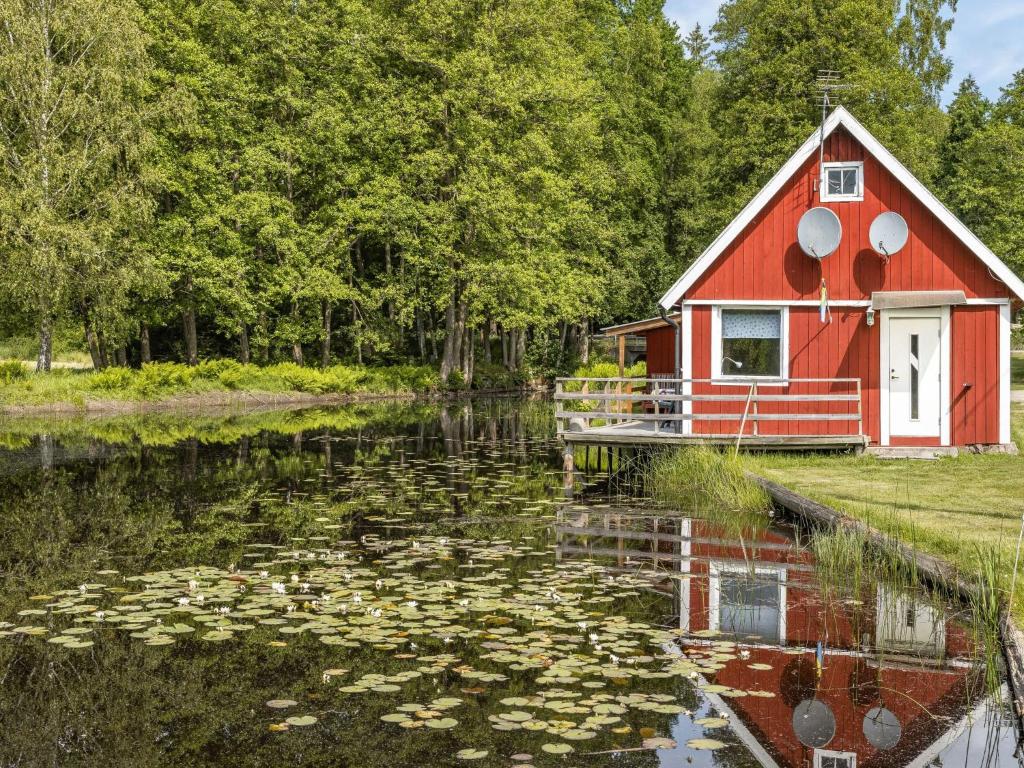 una casa roja en medio de un estanque con lirios en Holiday Home Tingsmåla by Interhome en Tingsryd