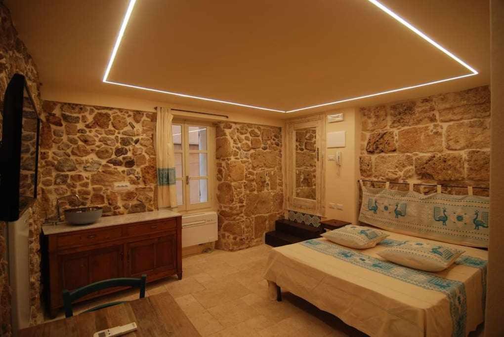 アルゲーロにあるSuite Principe Umberto Alghero Centralissimaの石壁のベッドルーム1室(ベッド1台付)