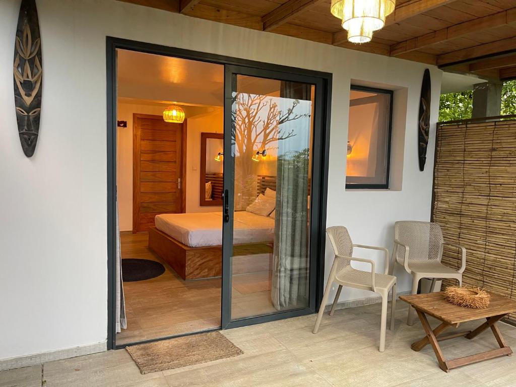 a room with a glass door with a bed and a table at Le Jardin Exotique Hotel in Diego Suarez