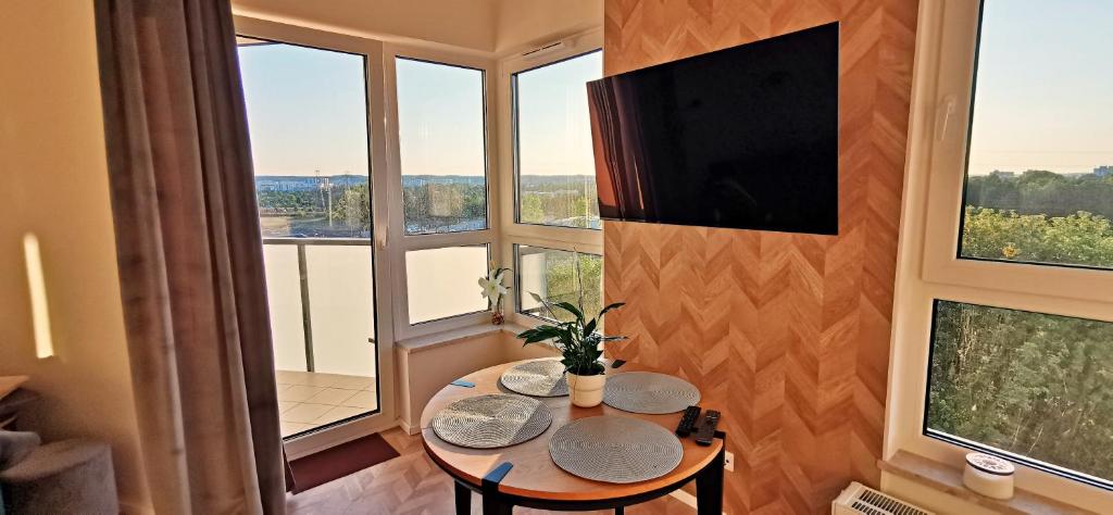 グダニスクにあるSłoneczny Apartamentのテーブル、テレビ、窓が備わる客室です。