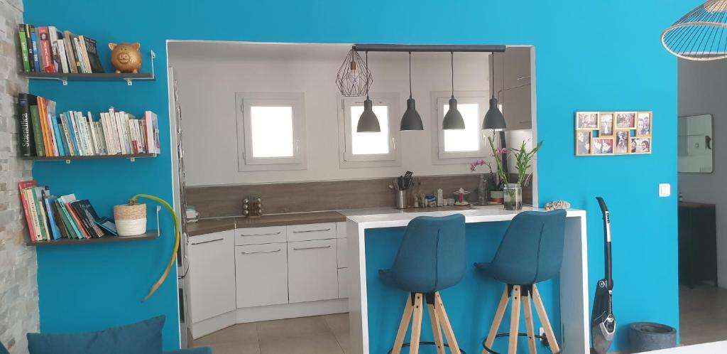 a kitchen with blue walls and a sink and stools at Maison bord de mer in Marseille