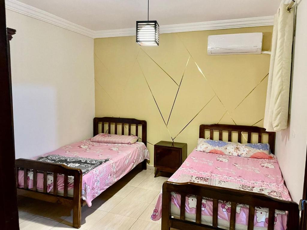duas camas num quarto com lençóis cor-de-rosa em DIMORA CHARMING CHALET em Dawwār ‘Abd al ‘Aţī Abū ‘Ajūz
