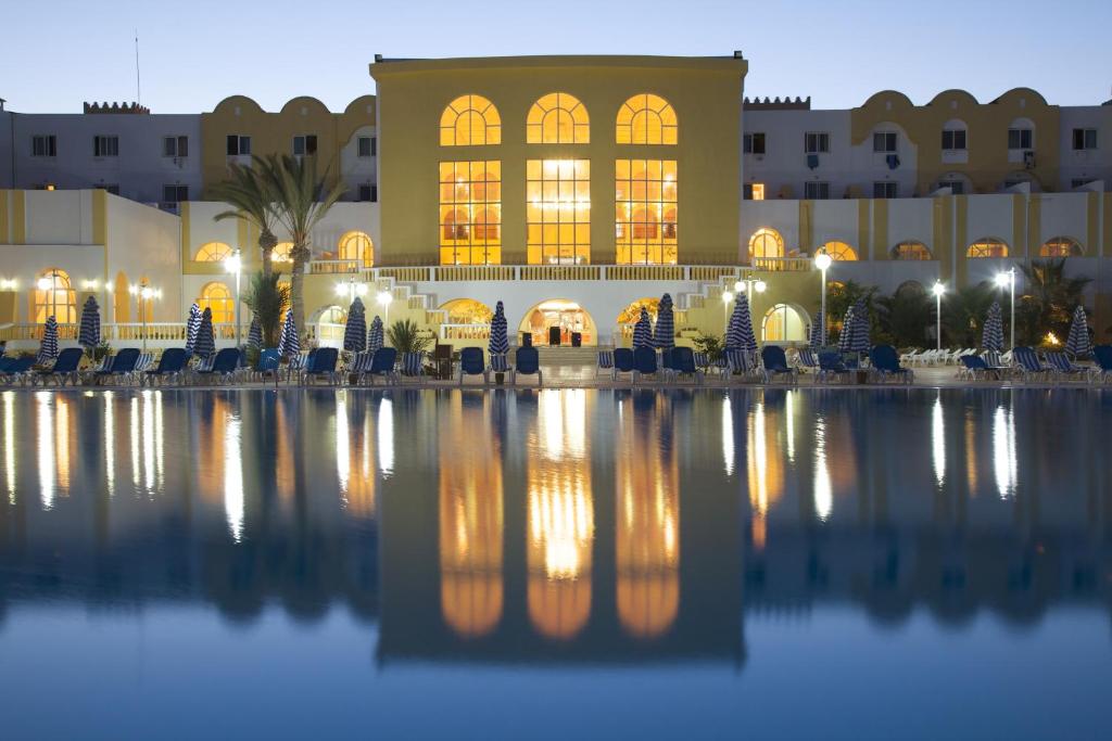 een gebouw met een reflectie in het water 's nachts bij Djerba Castille in Aghīr