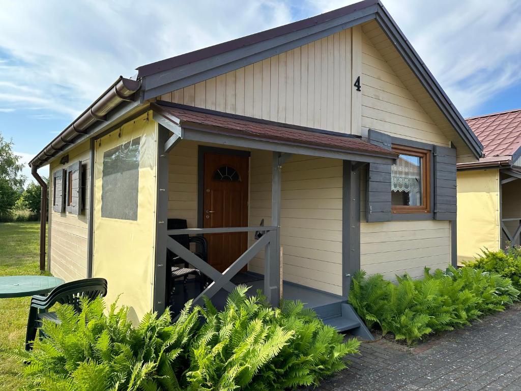 una casita amarilla con puerta de madera en Jantar Rodzinne Domki, en Bobolin