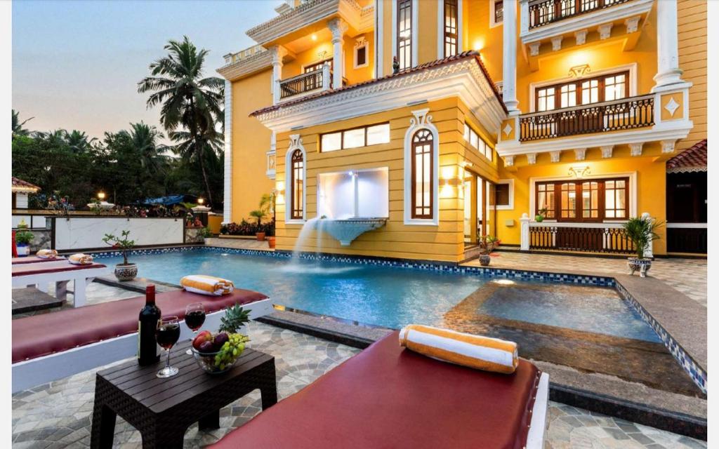 a villa with a swimming pool in front of a house at Anthy’s à la Campagne in Benaulim