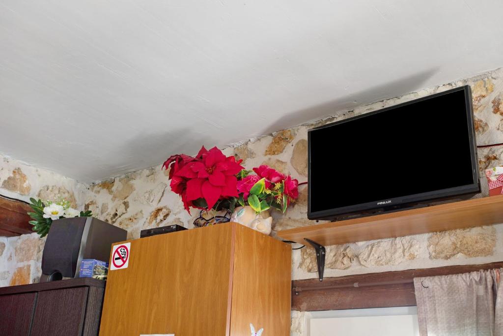 een flatscreen-tv die bovenop een muur staat bij Lithahiro stone house in Kerion