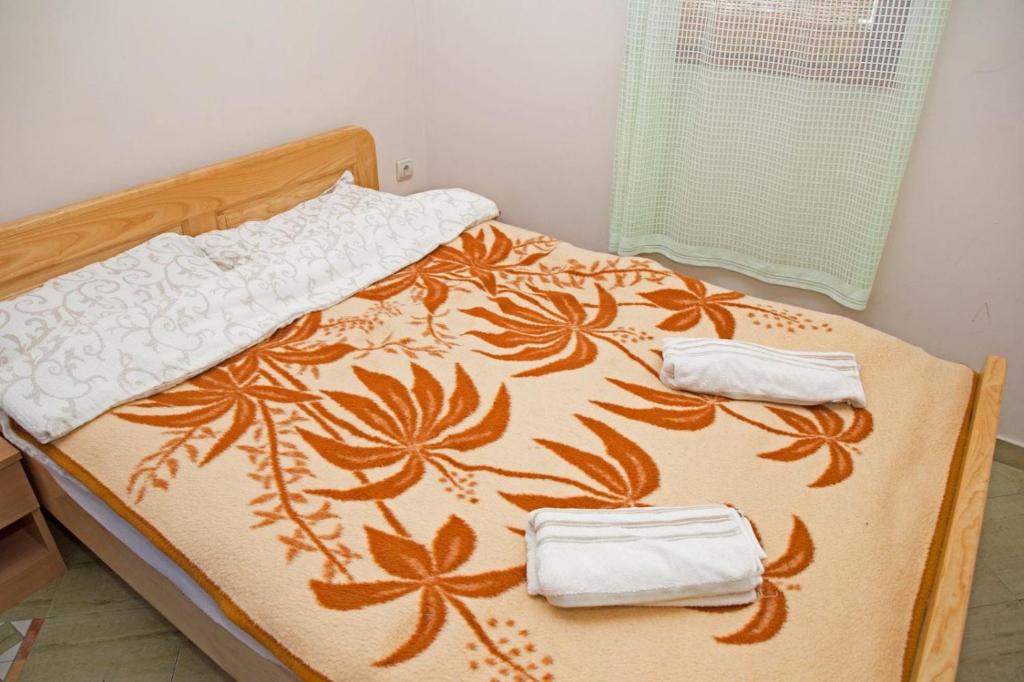a bed with an orange and white blanket and towels at Apartman Sunce in Golubac
