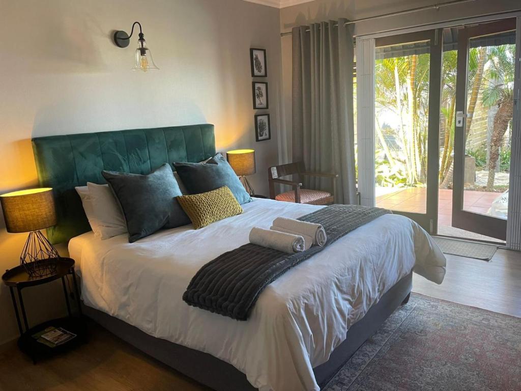 a bedroom with a large bed with a green headboard at Lazydaze Point in Jeffreys Bay