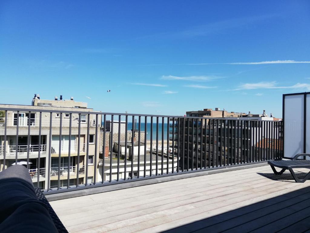 a person sitting on a balcony looking out at the city at Koksijde Penthouse in Koksijde