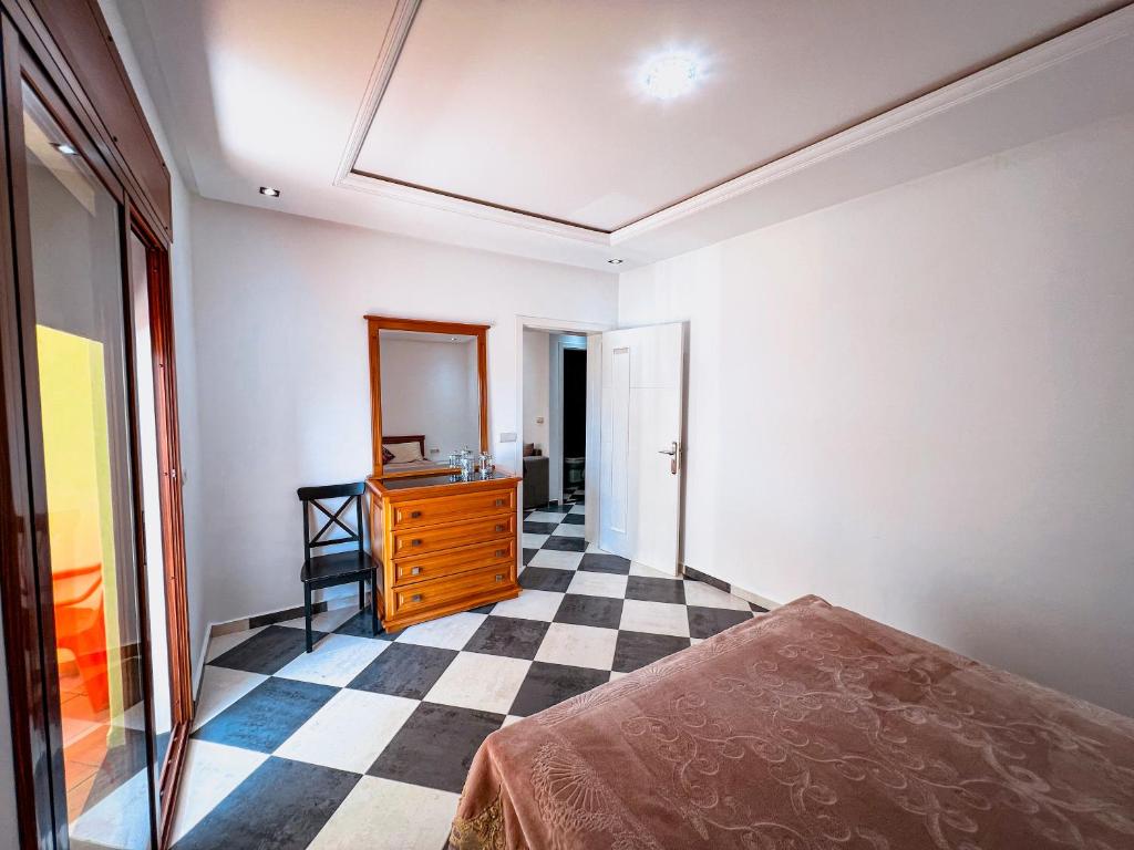 a bedroom with a bed and a dresser on a checkered floor at Visit Oued Laou - Florencia in Oued Laou