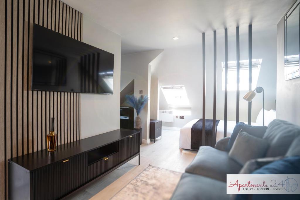een woonkamer met een bank en een tv aan de muur bij Beautiful Studio Apartment - London in Hounslow