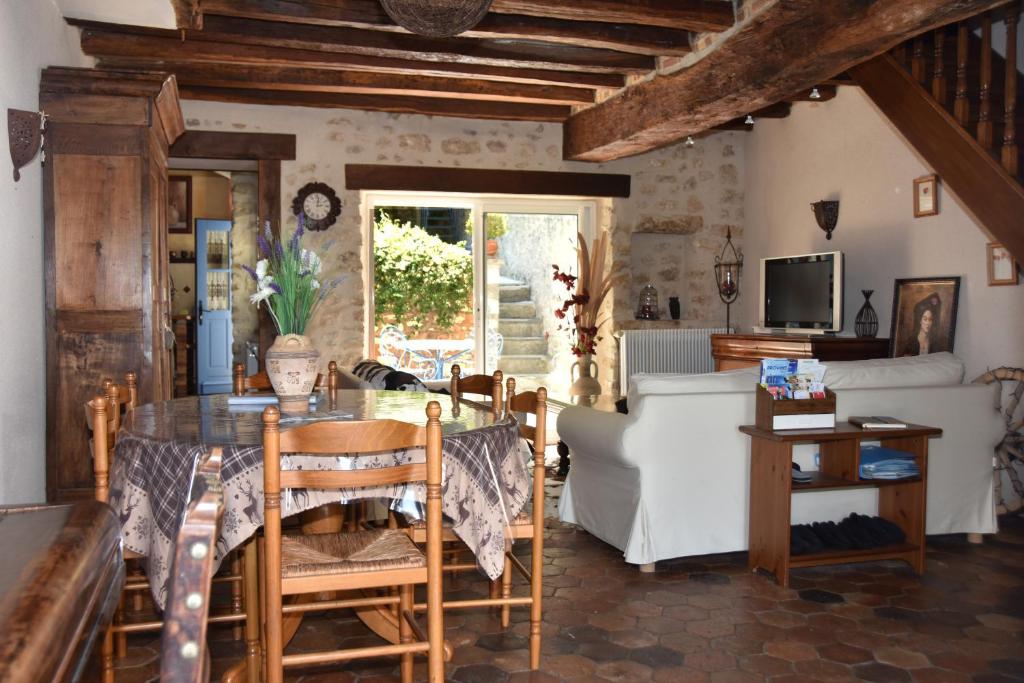 uma sala de estar com uma mesa de vidro e cadeiras em Les Volets Bleus em Provins