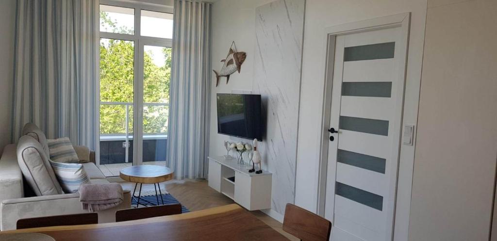 a living room with a couch and a tv at Apartament Happy 46 Hampton z klimatyzacją - tuż przy plaży!!! in Sianozety