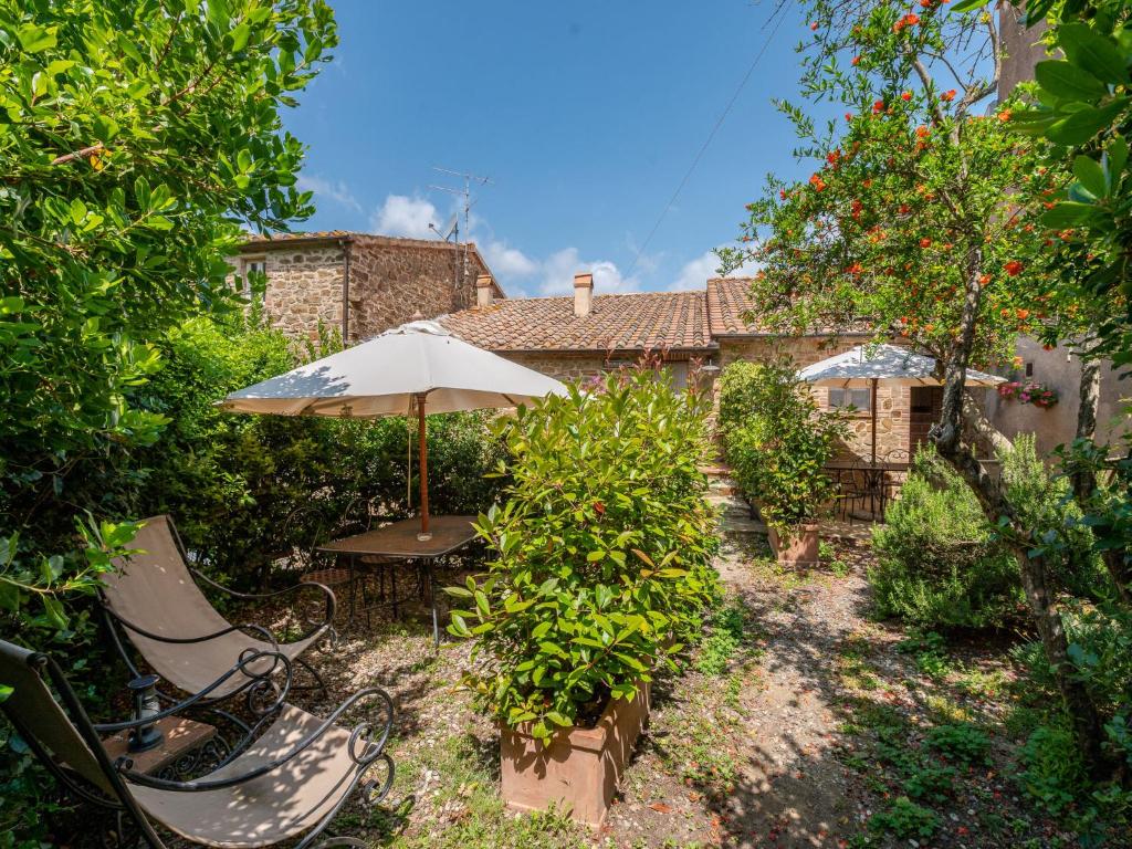 einen Garten mit zwei Stühlen und einem Sonnenschirm in der Unterkunft Holiday Home Olinto by Interhome in Cinigiano