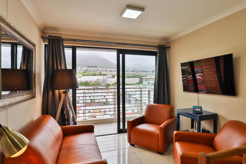 a living room with leather furniture and a large window at Chapel Towers 79 by CTHA in Cape Town